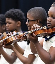 Orchard Richmond and Peter Paul RVA program participants, Isoke Chandler, Gilbert Carter, Marquise Oliver and Nina Chandler (from right) pluck their violin strings during a spring concert May 22 at Peter Paul RVA.