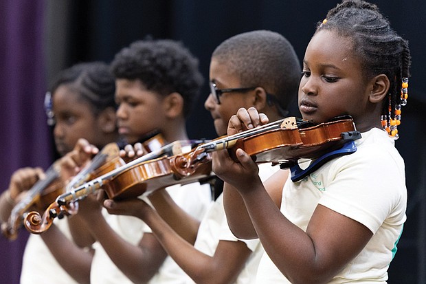 Orchard Richmond and Peter Paul RVA program participants, Isoke Chandler, Gilbert Carter, Marquise Oliver and Nina Chandler (from right) pluck their violin strings during a spring concert May 22 at Peter Paul RVA.