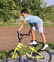 Amarii Clayton, 7, rides his bike in Dock Street Park on Saturday, May 31. Warmer temperatures are expected this week as summer returns to the region.