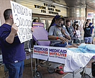 Tony Hedgepeth, a home care worker, speaks from a hospital gurney during a protest outside the Hippodrome. The gurney symbolized how proposed Medicaid cuts could threaten access to care for thousands of Virginia families.