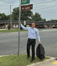 Jon Lugbill stands next to the new street sign for Honorary Jon Lugbill Drive outside the Sports Backers headquarters in Henrico County. Lugbill is retiring this month after 32 years as executive director.