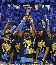 Oklahoma City Thunder guard Shai Gilgeous-Alexander, center, holds up the MVP trophy as he celebrates with his team after they won the NBA basketball championship with a Game 7 victory against the Indiana Pacers Sunday, June 22, in Oklahoma City.