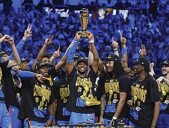 Oklahoma City Thunder guard Shai Gilgeous-Alexander, center, holds up the MVP trophy as he celebrates with his team after they won the NBA basketball championship with a Game 7 victory against the Indiana Pacers Sunday, June 22, in Oklahoma City.