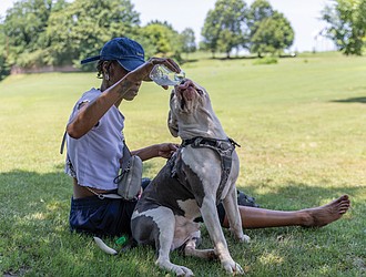 Lakea Lawrence offers her dog Tha Carter water while cooling off in the shade near Brown’s Island on Tuesday, June 24, as temperatures neared 100 degrees.