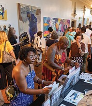 Jasmine Finnie and Jericia Johnson look at prints by mixed media artist Kelly U. Johnson at her table during the opening.