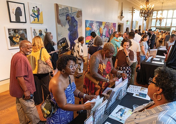 Jasmine Finnie and Jericia Johnson look at prints by mixed media artist Kelly U. Johnson at her table during the opening.