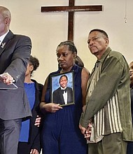 Vivian Sterling, center, and William Peoples stand with a photo of their son, Jabari Peoples, as attorney Ben Crump, far left, speaks to reporters during a press conference in Homewood, Ala., Tuesday, July 8, 2025.