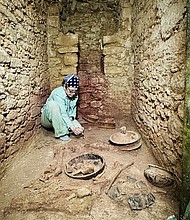 Diane Z. Chase in the tomb of Te K’ab Chaak with vessels in the foreground and jadeite mask to the left and the south wall niche./