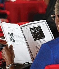 A guest reads the program during the ceremony. The firefighters’ hiring on July 1, 1950, marked a significant step forward in the struggle for civil rights.