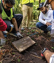 Ahsan Khan, left, and Umer Sindhu, right, along with other members of the Ahmadiyya Muslim Community and Friends of East End Cemetery, wash a newly uncovered gravestone.