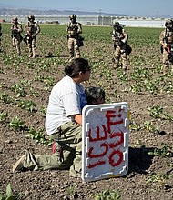 A demonstrator kneels Thursday before federal agents in a farm field during an immigration raid in Camarillo, California.
Mandatory Credit:	Michael Owen Baker/AP via CNN Newsource