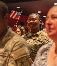 Tomisin Naomi Liadi, a member of the Army National Guard, waves a U.S. flag during the naturalization ceremony.