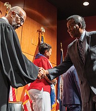 Collins Botchway of Ghana shakes hands with the Hon. Roger L. Gregory, chief judge of the U.S. Court of Appeals for the 4th Circuit, as he crosses the stage and officially becomes a U.S. citizen.