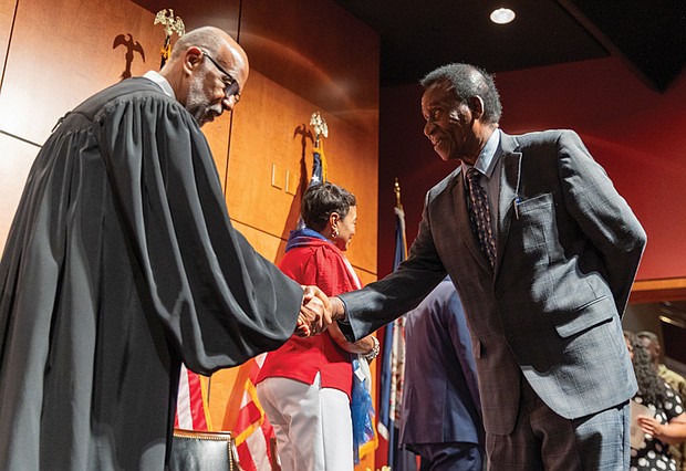 Collins Botchway of Ghana shakes hands with the Hon. Roger L. Gregory, chief judge of the U.S. Court of Appeals for the 4th Circuit, as he crosses the stage and officially becomes a U.S. citizen.