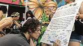 Outside Diversity Richmond on Tuesday, July 15, ahead of a community town hall, Stephanie Foreman holds a sign for Logan Wade to sign. The message supports a Diversity Richmond employee who reported being sexually assaulted and subjected to racism by a coworker.