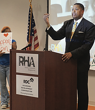 RRHA CEO Steven Nesmith stands alongside Gilpin Court residents holding signs in support of a proposed transfer of the public housing complex to a nonprofit subsidiary, following a news conference announcing a delay in the vote on the plan.