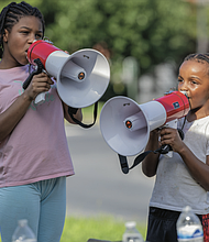 Siblings Destiny Moore, 10, and Antonio Silas, 8, chant into megaphones on the median of Monument Avenue as drivers pass by waving flags and signs, honking horns and greeting fellow protesters during the “Good Trouble Lives On” demonstration.