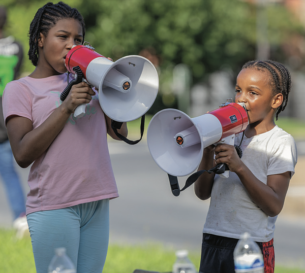 Siblings Destiny Moore, 10, and Antonio Silas, 8, chant into megaphones on the median of Monument Avenue as drivers pass by waving flags and signs, honking horns and greeting fellow protesters during the “Good Trouble Lives On” demonstration.