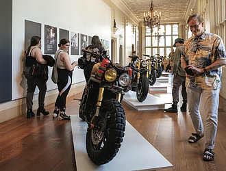 A visitor checks out a custom motorcycle on display at the “Ruined + Refined” exhibition, featuring unique builds and Vespa scooters. The exhibitions continue through Aug. 31.