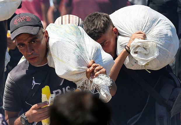 Palestinians seeking aid from the U.S.-backed Gaza Humanitarian Foundation carry bags, near Rafah, in the southern Gaza Strip, July 24.
Mandatory Credit:	Ramadan Abed/Reuters via CNN Newsource