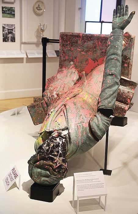 The Jefferson Davis statue, erected in 1907 on Monument Avenue and pulled down by protesters on June 10, 2020, is shown as part of a temporary exhibit at The Valentine. The former Confederate leader appears splattered with pink paint, with a blackened face and a dent on the back of the head from the 2020 protest.