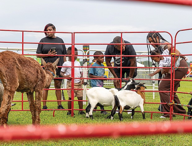 Zymeir Parker, 5, left, Tamika and James Wilson Jr. with their 5-year-old son, James Wilson III, center, and Jazmin Woodson with her 1-year-old daughter, Navy Woodson, right, interact with farm animals at the petting zoo.