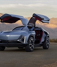 Front 3/4 view of the Cadillac Elevated Velocity concept in Vapor Blue with the gull-wing doors open with the desert in the background.