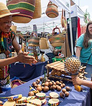 Abdul, with Mak Crafts, shows 8-year-old Dallas Clarke a hand crafted instruments at the 43rd Annual Carytown Watermelon Festival in Carytown on Sunday Aug 10. The event filled Cary Street with more than 100 vendors and artisans selling everything from crafts and teas to food, cups of fresh watermelon, and watermelon-flavored treats and drinks. The event featured live music across five stages, with additional small entertainment acts scattered throughout the street. Activities for all ages included face painting, a children’s area, and carnival rides.