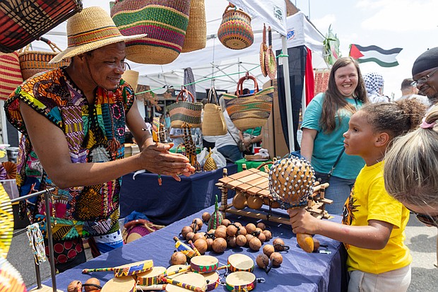 Abdul, with Mak Crafts, shows 8-year-old Dallas Clarke a hand crafted instruments at the 43rd Annual Carytown Watermelon Festival in Carytown on Sunday Aug 10. The event filled Cary Street with more than 100 vendors and artisans selling everything from crafts and teas to food, cups of fresh watermelon, and watermelon-flavored treats and drinks. The event featured live music across five stages, with additional small entertainment acts scattered throughout the street. Activities for all ages included face painting, a children’s area, and carnival rides.