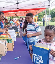 Unique Bolden, 6, checks her school supply bag while her cousin, Jeremiah Richardson, waits his turn at Speaking Spirit Ministries in Richmond on Saturday, Aug. 16, for Urban One Inc.’s Prep for Success Back to School Bash, receiving free supplies and community resources.