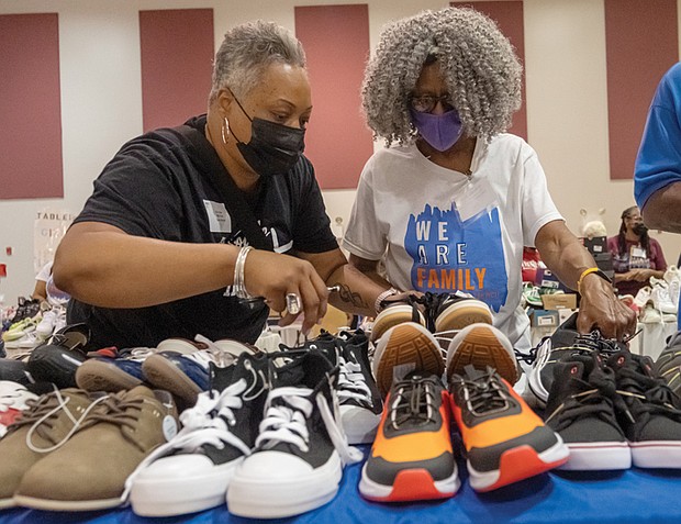 Volunteers Kim Allen and Willnette Beard browse shoes for student shoppers at the 19th annual New Shoes for Back to School event organized by the Metropolitan Richmond Partnership of Churches/Synagogues with participants from congregations across the area gave Richmond-area students new shoes to start the school year. Families lined up at a local church to pick shoes by size, enjoy live music, and take part in a voter registration drive.