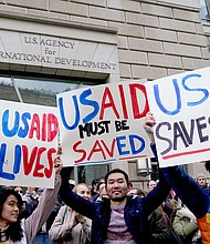 People hold placards, as the USAID building sits closed to employees after a memo was issued advising agency personnel to work remotely, in Washington, D.C., U.S., February 3.
Mandatory Credit:	Kent Nishimura/Reuters via CNN Newsource