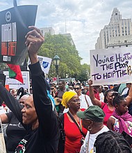 Protesters march on Wall Street in New York on Aug. 28 to denounce companies abandoning diversity, equity and inclusion initiatives. Left, The Rev.
