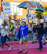 Gale Mumford, Anna Riddle and Al Brookwell cheer and wave as they march west down Broad Street during the “Workers Over Billionaires” Labor Day March.