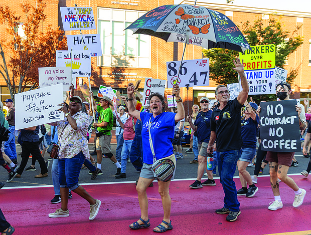 Gale Mumford, Anna Riddle and Al Brookwell cheer and wave as they march west down Broad Street during the “Workers Over Billionaires” Labor Day March.