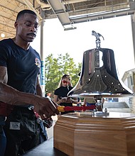 Tyrell Austin, a firefighter with Henrico Fire Division Station 5, rings a bell in honor of a fallen firefighter after completing the stair climb.