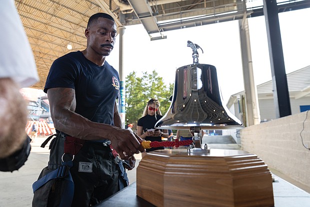 Tyrell Austin, a firefighter with Henrico Fire Division Station 5, rings a bell in honor of a fallen firefighter after completing the stair climb.