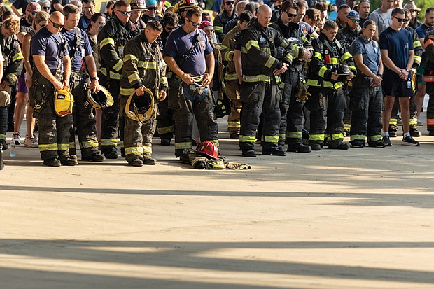 Firefighters, first responders and community members bow their heads in a moment of silence during the opening ceremony Saturday, Sept. 6 at
Richmond Raceway after completing the Metro Richmond 9/11 Memorial Stair Climb. The event honors first responders who died on Sept. 11, 2001,
and those who later died from related health complications. Participants climbed 2,200 steps, representing the 110 stories of the World Trade Center,or walked a 5K around the track. For more photos, see A3.