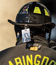 A badge remembering a fallen firefighter hangs from the back of a
firefighter’s helmet at the event.