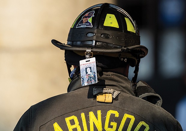 A badge remembering a fallen firefighter hangs from the back of a
firefighter’s helmet at the event.