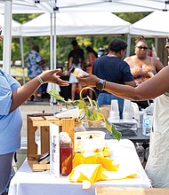 Faith Wilkerson buys a wellness drink from Tiffany Robinson, owner of The Tè Spot, selling teas and tonics during The WELL Fest.