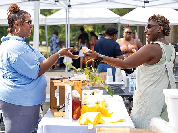 Faith Wilkerson buys a wellness drink from Tiffany Robinson, owner of The Tè Spot, selling teas and tonics during The WELL Fest.
