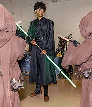 Left, Jadin Whitaker, dressed as a Sith Lord from “Star Wars,” meets two young Jawas,the hooded scavenger characters from the Star Wars universe, at the raceway.