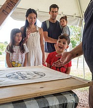 Native Arts Shine at Lewis Ginter-The inaugural Kennanee Native Arts Festival brought Indigenous art, culture and community to Lewis Ginter Botanical Garden on Sunday. Created with the Virginia Native Arts Alliance and Indigenous voices from across the East Coast, the festival featured music, storytelling, crafts, seed-saving, short films, a live Shinny game and an arts market. From left, Zelda, Suntary, Ben, Stellan and Thorin Wilcher look on as Erick Krigsvold of the Pamunkey Nation does screen printing. (Sandra Sellars/Richmond Free Press)