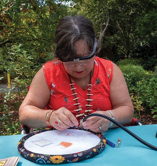 Native Arts Shine at Lewis Ginter-The inaugural Kennanee Native Arts Festival brought Indigenous art, culture and community
to Lewis Ginter Botanical Garden on Sunday. Created with the Virginia Native Arts Alliance and Indigenous voices from across the East
Coast, the festival featured music, storytelling, crafts, seed-saving, short films, a live Shinny game and an arts market. Tamsye Stover of The Chickahominy Beaded Turtle uses the Peyote stitch method to bead a stethoscope.