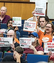 During the City Council’s public comment period at City Hall on Monday, Sept. 22, residents hold up signs calling for more affordable housing and stronger protections against rent gouging.