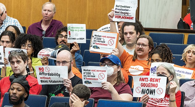 During the City Council’s public comment period at City Hall on Monday, Sept. 22, residents hold up signs calling for more affordable housing and stronger protections against rent gouging.