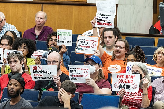 During the City Council’s public comment period at City Hall on Monday, Sept. 22, residents hold up signs calling for more affordable housing and stronger protections against rent gouging.