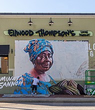 Cityscape-Slices of life and scenes in Richmond-Artist Jason Ford paints a mural Oct. 1 at Ellwood Thompson’s Local Market in Richmond as part of Fairtrade America’s national mural series for Fairtrade Month. The campaign highlights the often unseen farmers and workers who grow everyday products such as coffee, cocoa and bananas while drawing attention to the challenges they face from unfair trade practices. Ellwood Thompson’s was selected along with two other stores in Coralville, Iowa, and Sioux Falls, South Dakota, to participate in the project. The mural depicts Sierra Leone cocoa farmer Aminata Sannoh, whose cocoa is used by Hu Kitchen chocolate sold at Ellwood Thompson’s. Hu Kitchen, Fairtrade America, Ellwood Thompson’s and Ford will host Fairtrade Fest Oct. 18, when they will officially unveil the mural. (Julianne Tripp Hillian/Richmond Free Press)