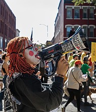 A demonstrator in clown makeup rallies the crowd with a bullhorn on Broad Street in Richmond during the No Kings protest. (Julianne Tripp Hillian/Richmond Free Press)